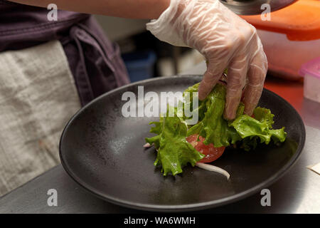 Les mains du chef de l'alimentation s'étend sur une plaque bleue close-up Banque D'Images