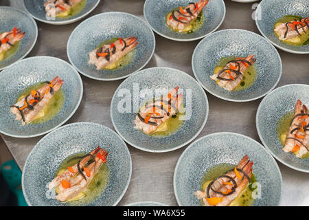 De nombreuses planches aux crevettes sur une table de cuisine dans un restaurant. Banque D'Images