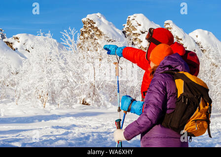 L'homme et de la femme dans les montagnes d'hiver regarder dans la distance qui se tenait à côté de lui contre l'harfang roches sur une froide journée ensoleillée Banque D'Images