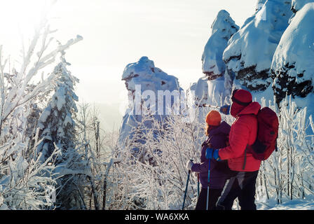 L'homme et de la femme dans les montagnes d'hiver regarder dans la distance qui se tenait à côté de lui contre l'harfang roches sur une froide journée ensoleillée Banque D'Images