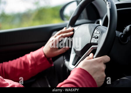 Man main tenant le volant de voiture - mâle part close up dof peu profonde profondeur de champ - voiture conduire les deux mains sur le mans volant dans la conduite Banque D'Images