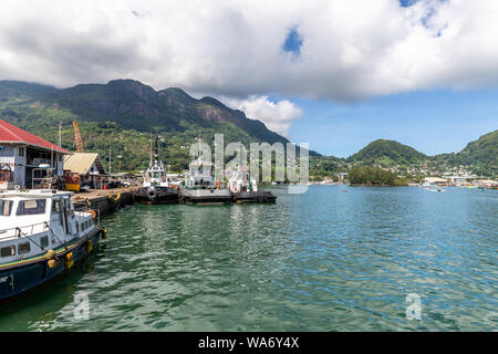 Port de Victoria sur l'île de Mahé aux Seychelles avec montagnes en arrière-plan, les navires et l'eau bleue à l'avant Banque D'Images