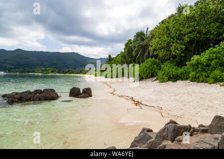 Paradise beach anse royale sur l'île de Mahé aux Seychelles avec turguoise l'eau, de palmiers, de sable blanc et de rochers de granit Banque D'Images