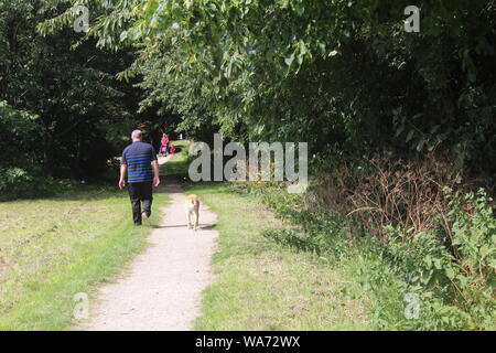 Man Walking dog le long du chemin près de l'Aire et Calder canal avec femme et enfant sur un après-midi d'été en Grande-Bretagne, Royaume-Uni Banque D'Images