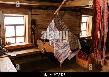 Fragment de l'intérieur d'un vieux paysan log cabin avec une station d'accueil, et les ceintures à motifs tissés quenouille Banque D'Images