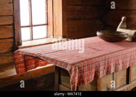 Fragment de l'intérieur d'un vieux paysan log cabin - une table avec des plats en bois, fait main et nappe tissée Banque D'Images