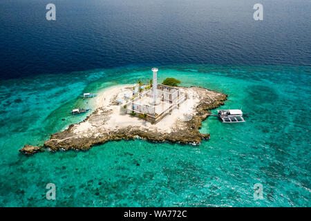 Vue aérienne drone d'embarcations traditionnelles à côté d'une petite île tropicale avec un phare, entourée de récifs de corail (Capitancillo Island, Philippines) Banque D'Images