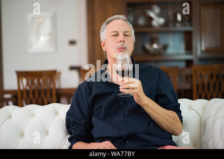 Portrait d'un homme mûr bénéficiant d''un verre de vin rouge à la maison Banque D'Images