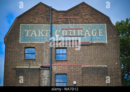 Bleu et blanc un "ghost" panneau disant "prenez courage' sur une façade en briques d'une ancienne brasserie dans le centre de Londres. Le format paysage. Banque D'Images