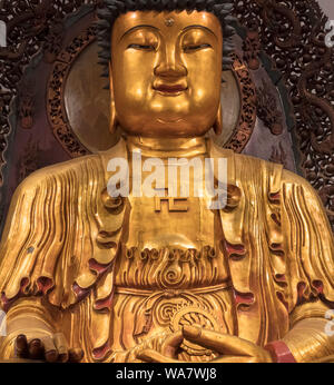 Croix gammée sur la poitrine d'une statue de Bouddha dans la Grande Galerie du Temple du Bouddha de Jade, Shanghai, Chine. Dans le bouddhisme, le svastika est considéré comme de bon augure pour symboliser les traces du Bouddha. Banque D'Images