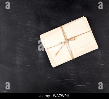 Vieilles cartes papier blanc vide attachés avec une corde sur un fond en bois noir, copy space Banque D'Images