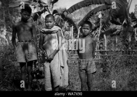 AJAXNETPHOTO. 1953-1957 (environ). INDO CHINE. Le VIETNAM. (Dans le pays EMPLACEMENT INCONNU.) - Trois jeunes garçons, l'un (au centre) avec le crâne rasé PORTANT Robe bouddhiste, DANS UN PAYSAGE DE PLANTATION. photo:JEAN CORRE/AJAXREF:RX7  240 191508 Banque D'Images