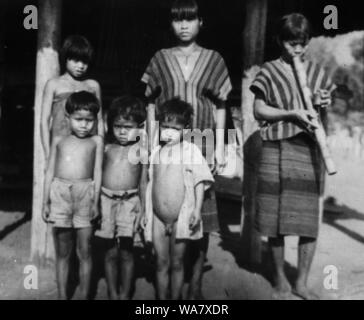 AJAXNETPHOTO. 1953-1957 (environ). INDO CHINE. Le VIETNAM. (Dans le pays EMPLACEMENT INCONNU.) - groupe de filles, l'un fumer une pipe à eau EN BAMBOU ET LES JEUNES GARÇONS POSENT POUR LA CAMÉRA À L'EXTÉRIEUR DE MAISON SUR PILOTIS. photo:JEAN CORRE/AJAXREF:RX7  242 191508 Banque D'Images