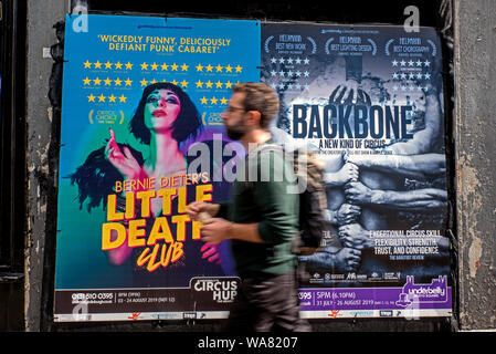Un jeune homme marchant par affiches publicitaires pour Edinburgh Fringe Festival montre. Edinburgh, Ecosse, Royaume-Uni. (With motion blur) Banque D'Images