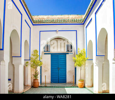 Courtyard at El Palais Bahia, Marrakech, Maroc. il y a des murs blancs et des colonnes avec des panneaux bleus et portes bleues. Banque D'Images