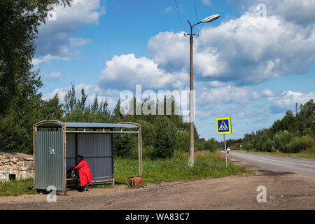 La Russie, le 16 août - DÉMIANSK, 2019, Femme au manteau rouge examine les horaires de bus au magasin rural Banque D'Images