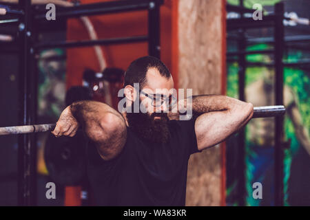 Jeune homme barbu faisant le levage de poids dans une salle de sport Banque D'Images