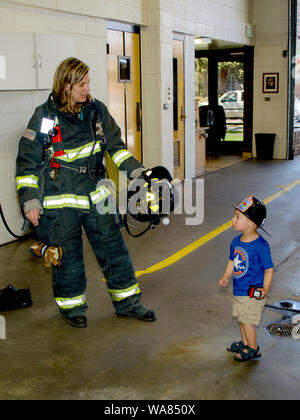 Thornton Colorado USA 14 juillet 2014 ; une pompière forestière montre comment un jeune garçon un peu d'uniforme est quand même quelqu'un essayer de les aider dans un incendie Banque D'Images