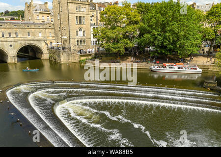 BATH, ANGLETERRE - Juillet 2019 : en forme de fer à cheval Le Pulteney Weir sur la rivière Avon et Pulteney Bridge dans le centre de Bath. Banque D'Images