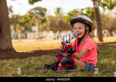 Petite fille en patins à l'eau potable à park Banque D'Images