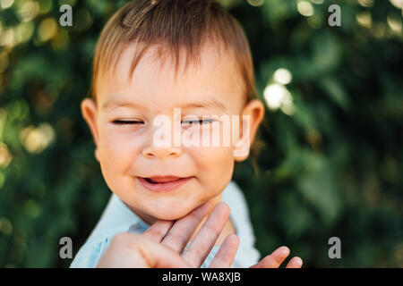 Happy Baby avec les yeux fermés et les mères hand touching chin Banque D'Images