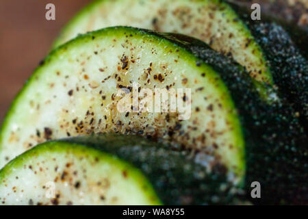 Les tranches de courgette saupoudré de sel et d'herbes. La courgette crue en close-up. Banque D'Images