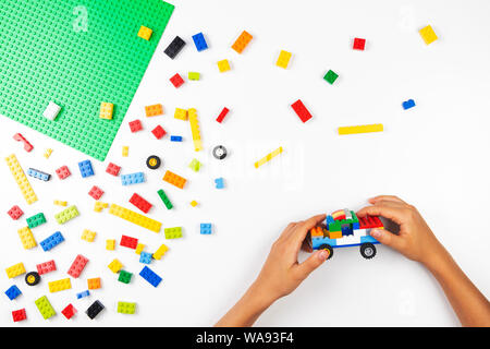 Vilnius, Lituanie - 17 août, 2019 : les mains de l'enfant jouer avec des blocs de Lego et de faire de nouvelle voiture sur tableau blanc Banque D'Images