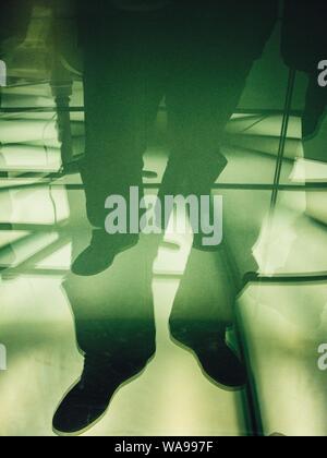 Photographie verticale en double exposition des pieds mâles sur un verre surface Banque D'Images
