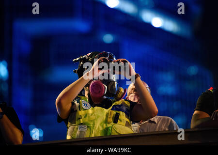 Hong Kong, Chine. Août 18, 2019. Au cours d'une action de protestation devant un bâtiment du gouvernement de Hong Kong dans le quartier central, un manifestant la police observe avec des jumelles. Dans l'ancienne colonie britannique de Hong Kong, les protestations contre l'influence de Beijing sont entrés dans un nouveau cycle. Le mouvement pour la démocratie avaient appelé à une autre grande manifestation. Credit : Gregor Fischer/dpa/Alamy Live News Banque D'Images