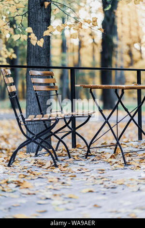 De l'automne. Table et chaises en bois dans le parc automne vide, tombée feuilles d'érable. Concept de l'humeur d'automne Banque D'Images