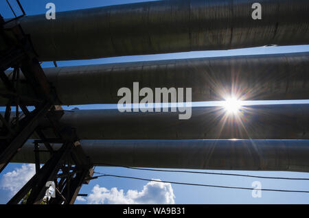 Soleil radieux et quatre tubes d'une centrale thermique sur le fond du ciel bleu Banque D'Images