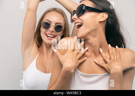 Blonde and brunette copines sont extrêmement satisfaits de leurs nouvelles lunettes isolé sur fond blanc Banque D'Images