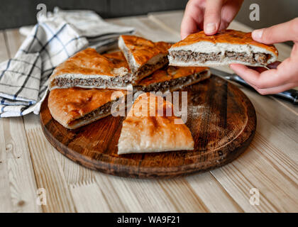 Ossètes traditionnels pâtés à la viande de boeuf avec main de femme avec Banque D'Images