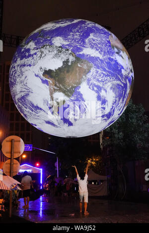 Les visiteurs interagissent avec GAIA, une installation artistique de terre rougeoyante par Luke Jerram artiste britannique, érigée sur le Bund en mémoire de 50e anniversaire de Banque D'Images