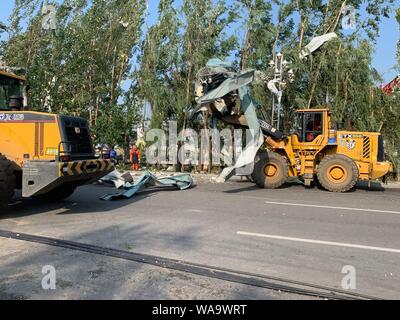 Les travailleurs chinois à déloger les débris d'arbres et poteaux télégraphiques brisée par des vents violents causés par une tornade dans la ville de Kaiyuan, Tieling city, au nord-est Banque D'Images