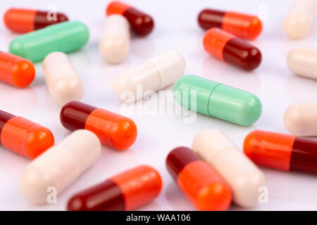 Les gélules et comprimés colorés isolé sur fond réfléchissant blanc. L'industrie pharmaceutique mondiale pour des milliards de dollars par année. Médicament pharmaceutique Banque D'Images