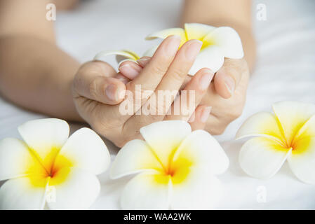 Main tenant belle dame blanche jaune plumeria flowers on lit blanc - les gens avec des fleurs spa concept esprit paisible Banque D'Images