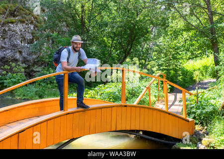 Concept de Tourisme, de voyage et de mode de vie. traveler avec carte. Un barbu en jeans et un t-shirt avec une carte dans ses mains se tient sur un pont. Sur Banque D'Images