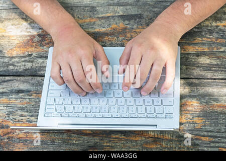 L'entreprise, de l'éducation, les gens et la technologie concept. Les hommes de mains avec clavier ordinateur portable sur fond de table en bois. Vue d'en haut. Banque D'Images