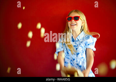 Little girl wearing Sunglasses and eating popcorn s'amusant Banque D'Images