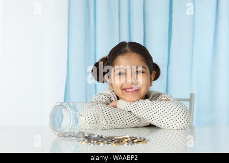 Girl sitting with her savings and smiling Stock Photo