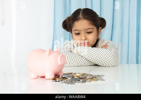 Fille assise avec son épargne et de penser Banque D'Images