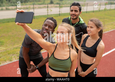 Très jolie jeune femme dans des vêtements de sport avec ses amis selfies sur stadium Banque D'Images