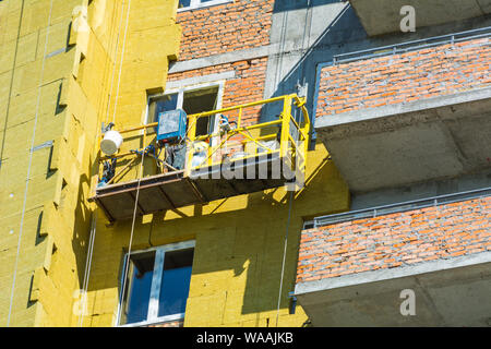 Travail à haute altitude sur les murs extérieurs de l'isolation en laine de verre et de plâtre Banque D'Images