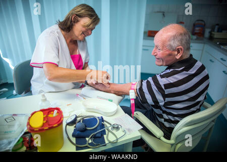Hohen Wangelin, Allemagne. 25 Juin, 2019. Veronica infirmière Timm prend des échantillons de sang de Günter Ludwig patient dans une salle de consultation dans la pratique de la 74-year-old country médecin Lothar Kruse. Le médecin généraliste a été le traitement des patients de la région dans son cabinet à Hohen Wangelin pendant 40 ans. À la fin de 2019, Kruse veut renoncer à sa pratique, mais n'a jusqu'à présent tenté d'obtenir un successeur. Credit : Jens Büttner/dpa-Zentralbild/ZB/dpa/Alamy Live News Banque D'Images