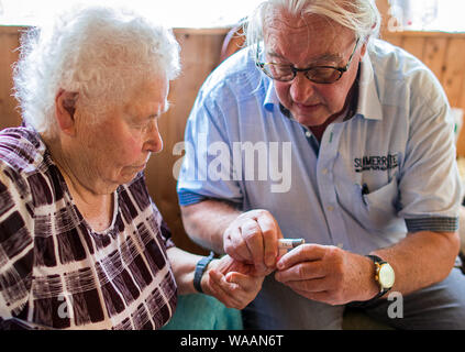 Neu Gaarz, Allemagne. 25 Juin, 2019. Le 74-year-old country médecin Lothar Kruse prend un échantillon de sang de son patient Elfriede Rennicke dans le porche de sa ferme au cours de sa visite à domicile. Le médecin généraliste a été le traitement des patients de la région dans son cabinet à Hohen Wangelin pendant 40 ans. À la fin de 2019, Kruse veut renoncer à sa pratique, mais n'a jusqu'à présent tenté d'obtenir un successeur. Credit : Jens Büttner/dpa-Zentralbild/ZB/dpa/Alamy Live News Banque D'Images