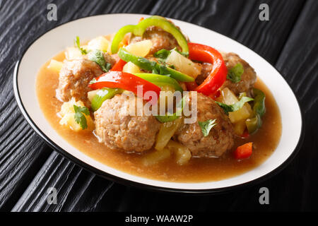 Boulettes asiatiques à l'étuvée avec ananas frais et poivrons dans une sauce aigre-douce close-up sur une plaque sur la table horizontale. Banque D'Images