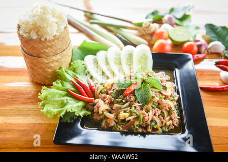 Salade de porc haché épicé Thai Food servi sur table avec des herbes et épices Ingrédients Riz collant au nord-est de tradition Isaan aliments délicieux sur plaque avec Banque D'Images