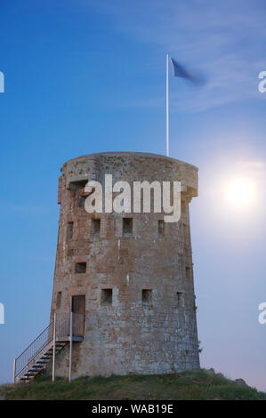 La Lune se levant derrière le HOCQ Michaël tour ronde à St Clement. L'un d'une série de forts historiques 22 construit autour de la côte de Jersey. Les îles de la Manche. Banque D'Images