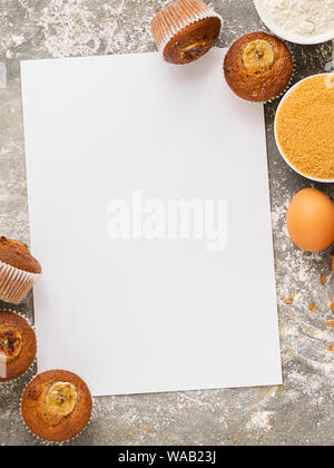 Des muffins aux bananes et ingrédients pour la cuisson sont disposés sur une feuille blanche. Dessert végétalien sain. Concept de saine alimentation. Châssis vertical Banque D'Images